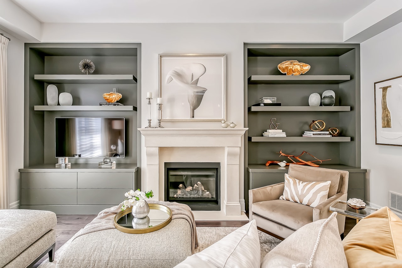 A living room with a fireplace, a couch, a chair, and a flat-screen TV at the side of the fireplace.