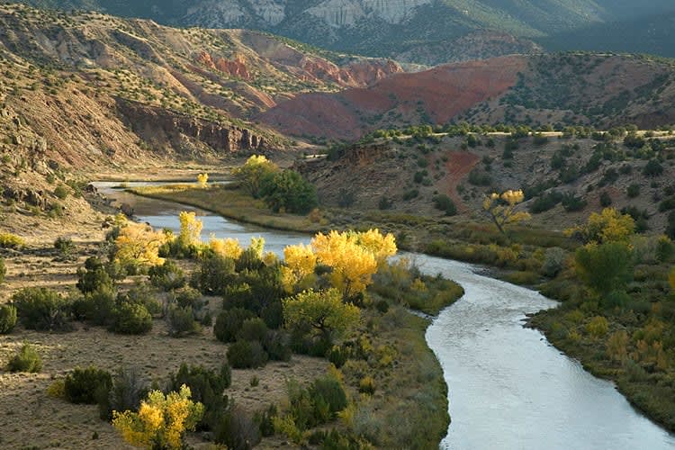 A river flowing through a valley with mountains in the background.