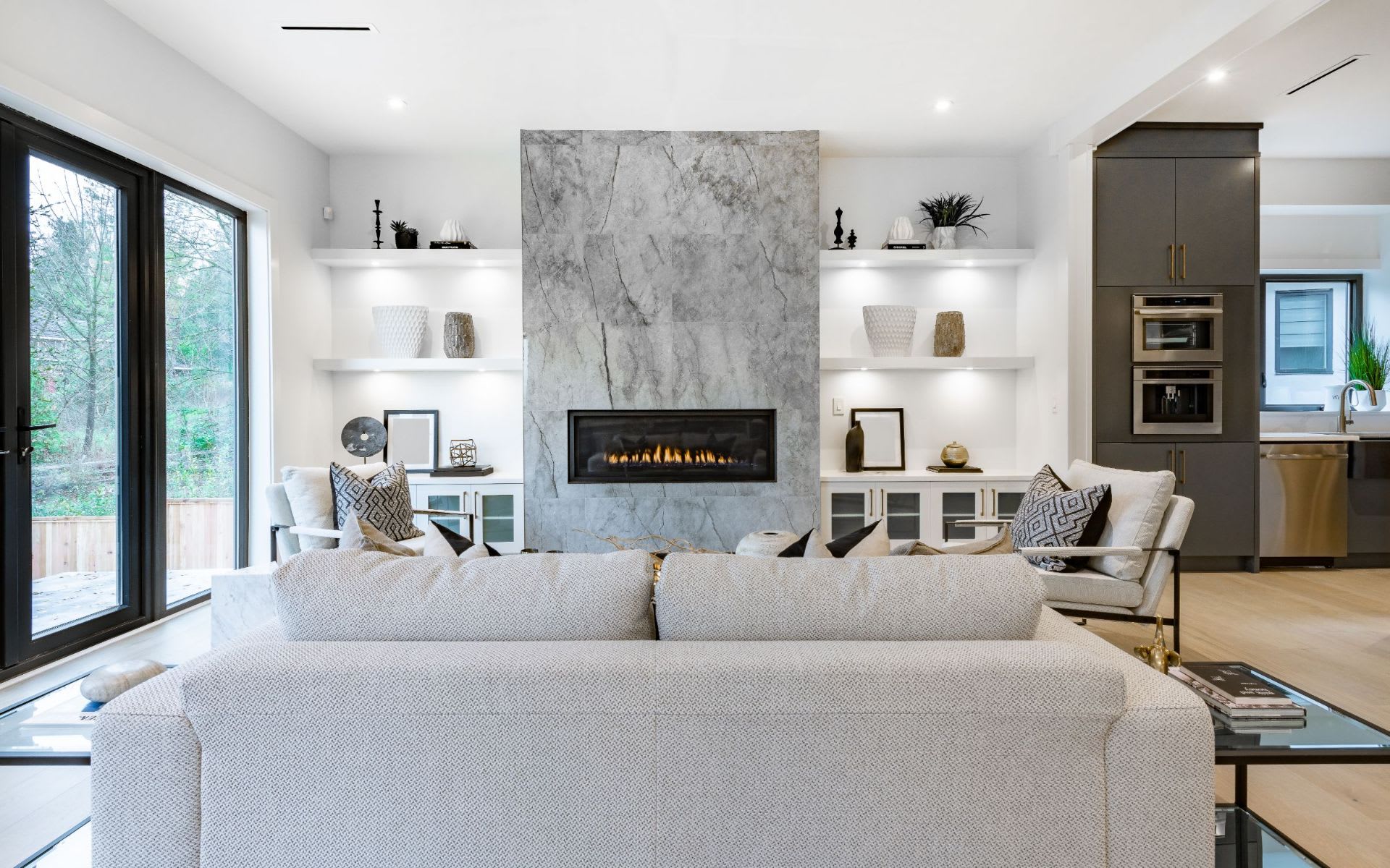 A spacious living room features a dark grey sofa with a textured fabric, accompanied by a light grey throw blanket draped over one arm.