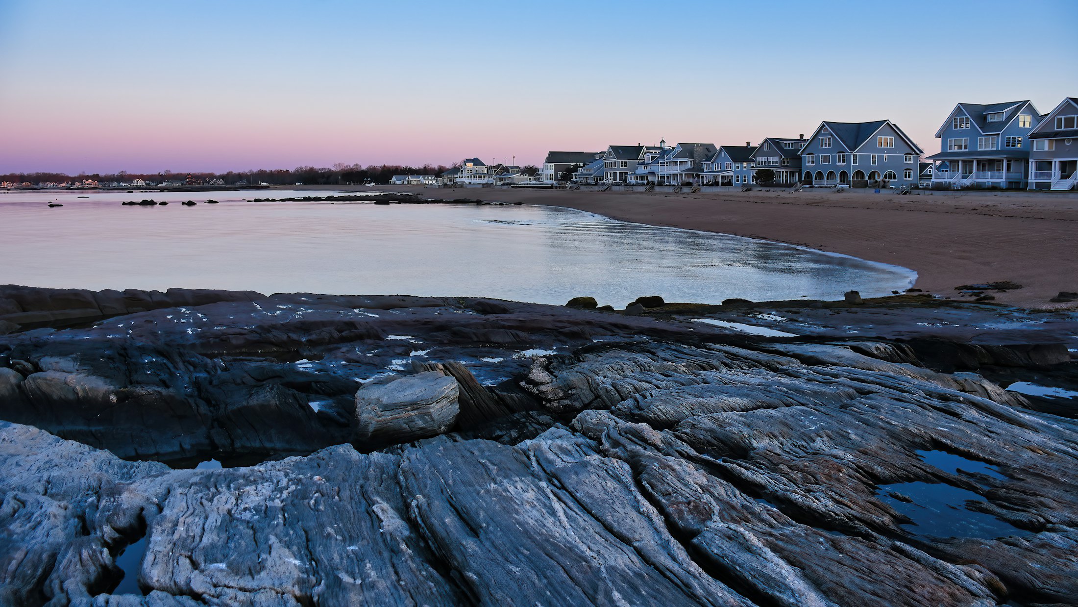 Shingle-style homes along a Connecticut beach at dusk
