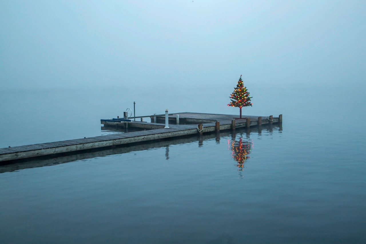 A Christmas tree on a dock in a foggy lake