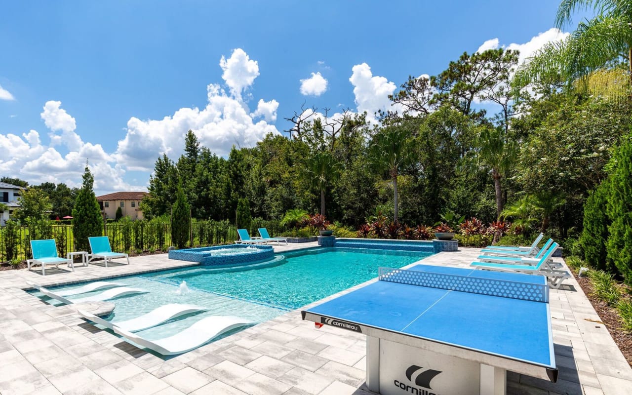 A rectangular swimming pool with a blue tile lining sits next to a green table tennis table.