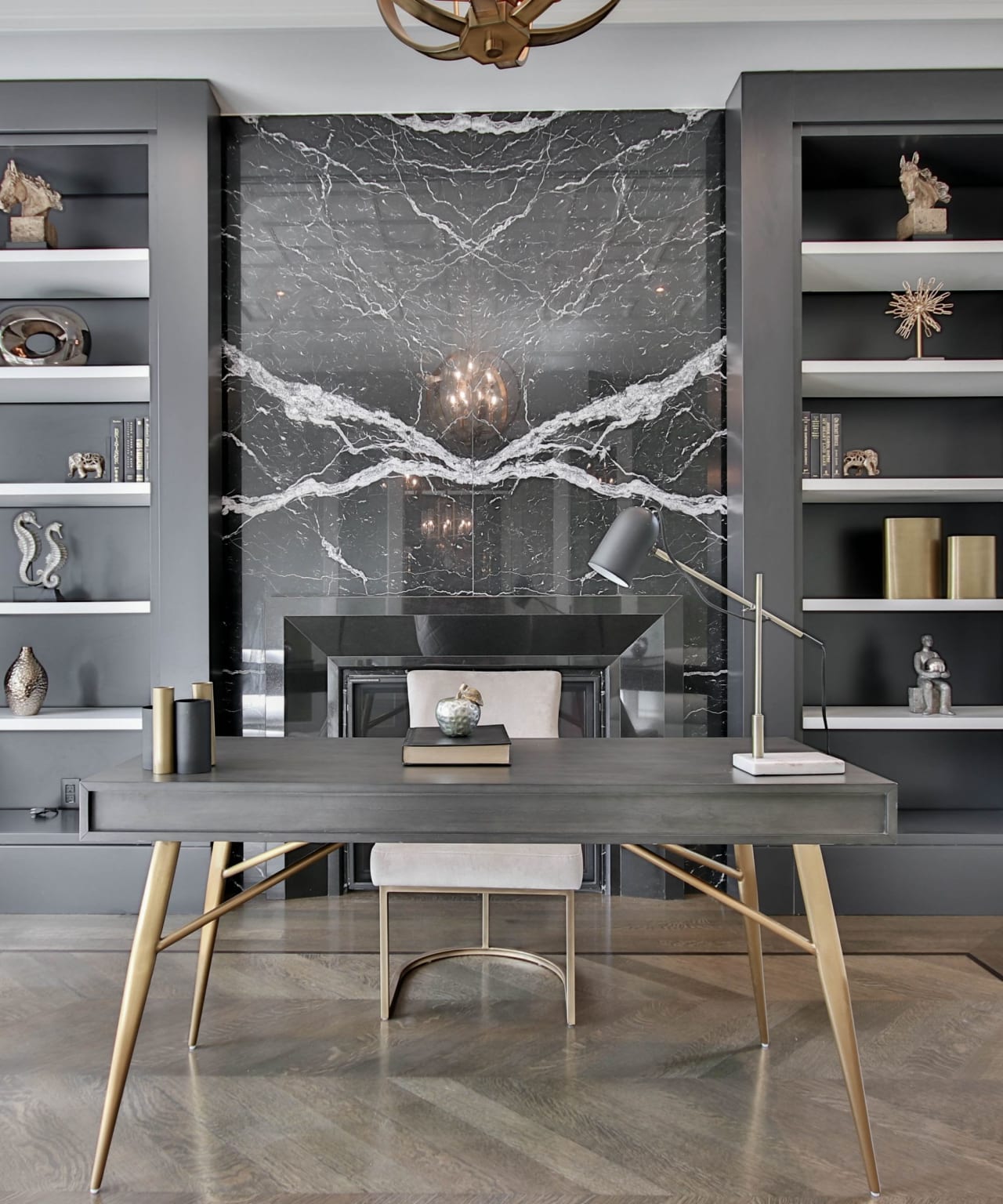 A modern home office with a desk and chair set up in front of a marble fireplace.