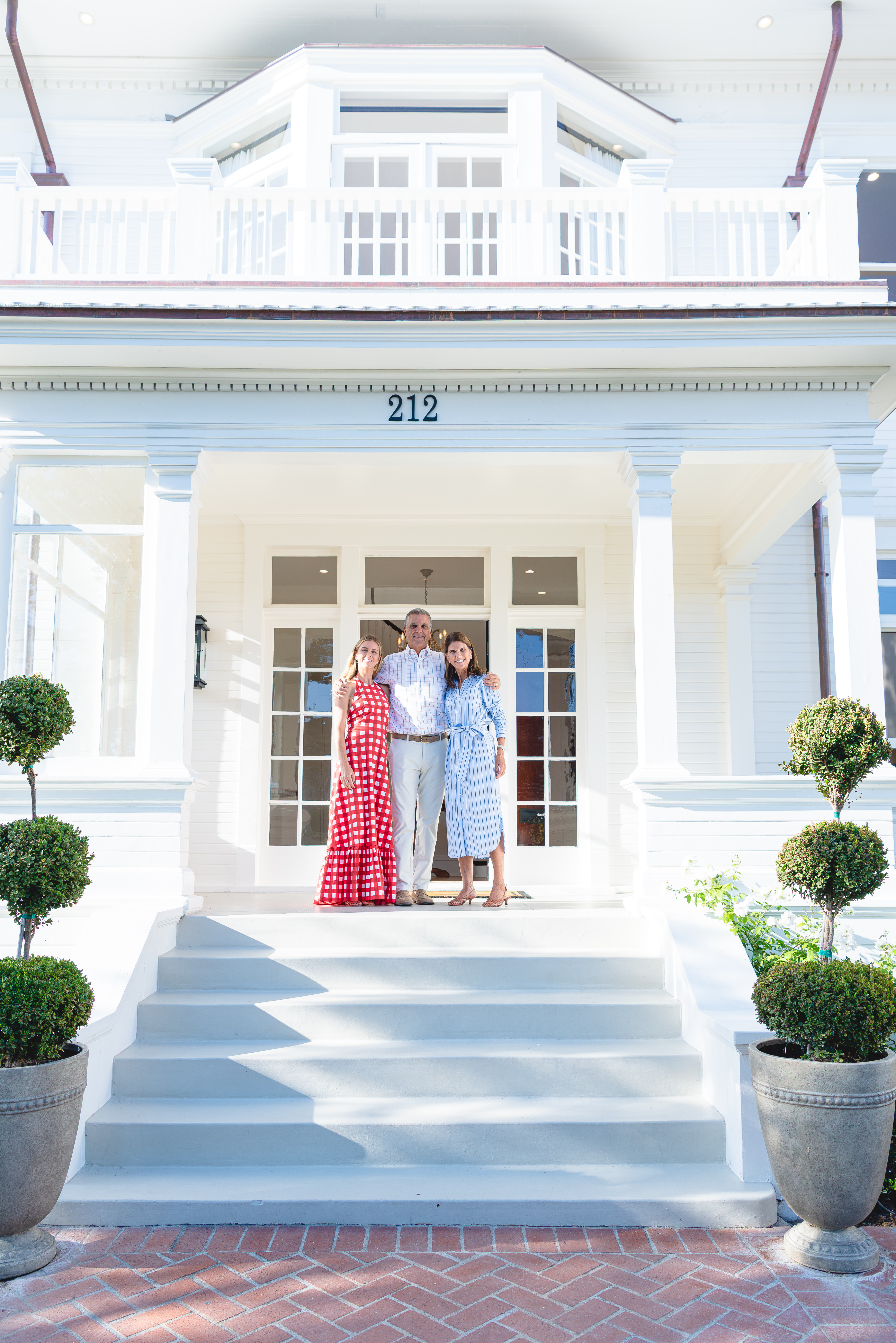 Hosts standing at the front doors at the top of the entry stairs