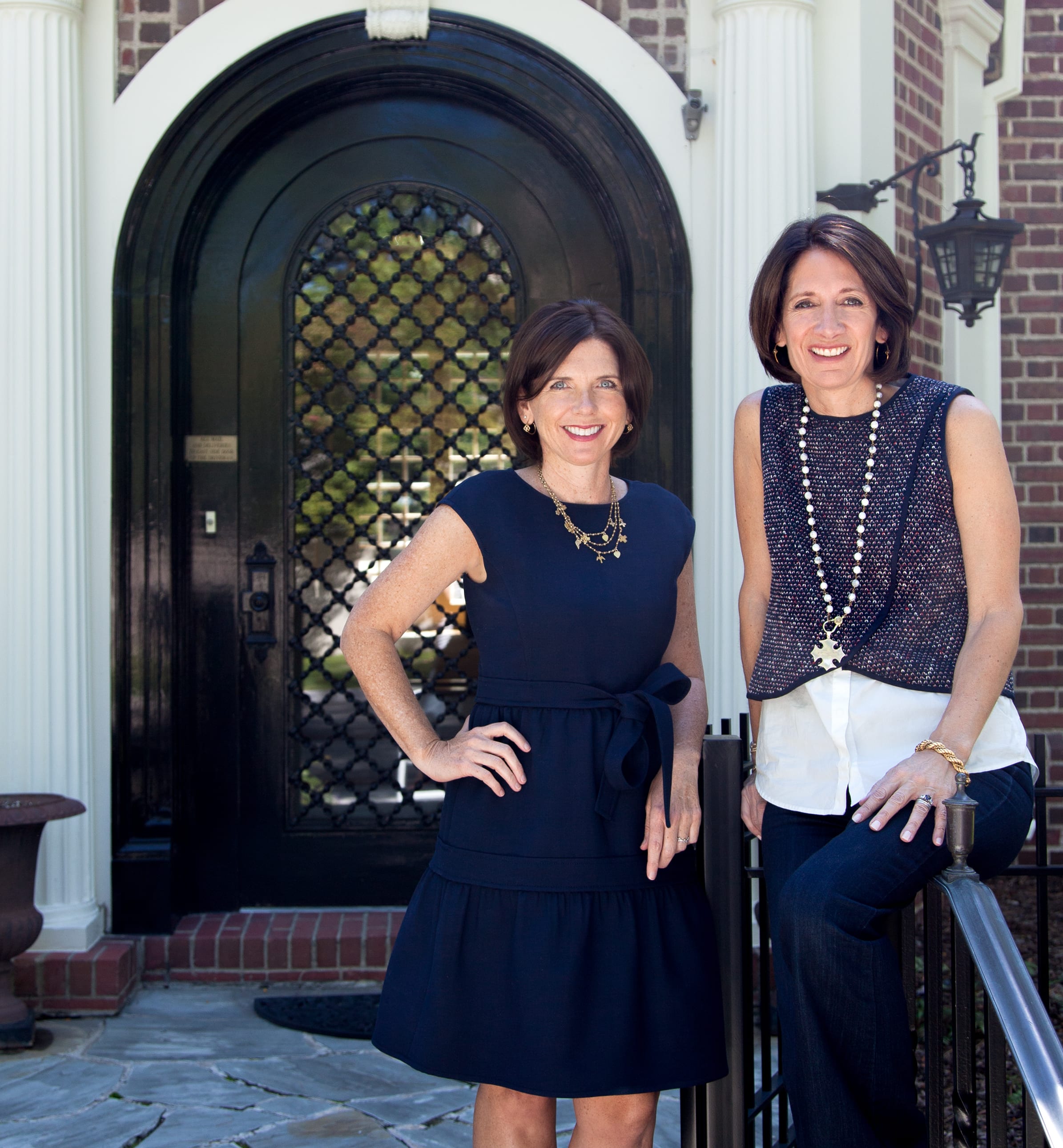 Trish & Maggie, smiling real estate experts, standing at the entrance of a luxury property.