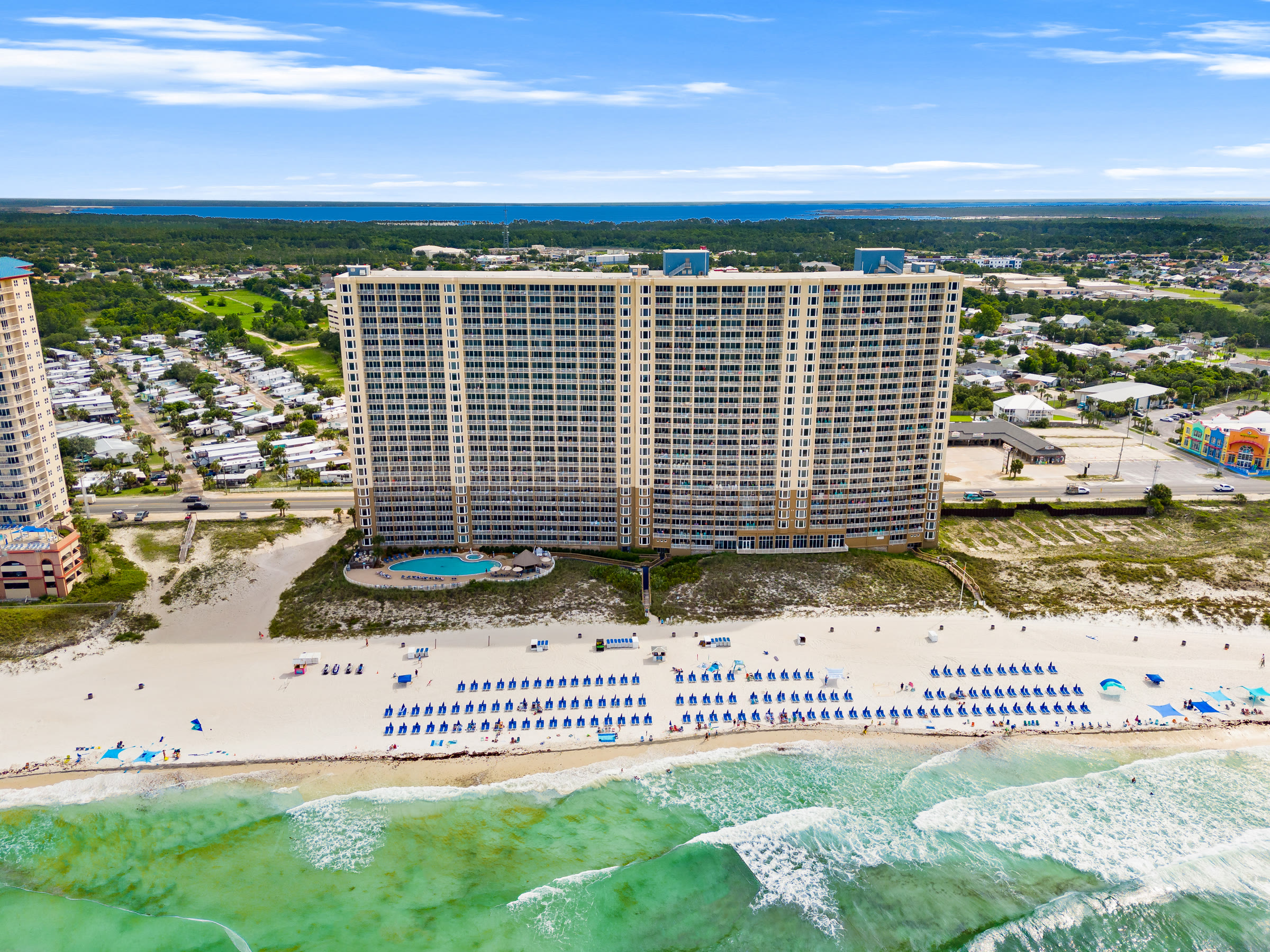 Aerial of a beachfront condo pool and beach umbrellas in Panama City Beach