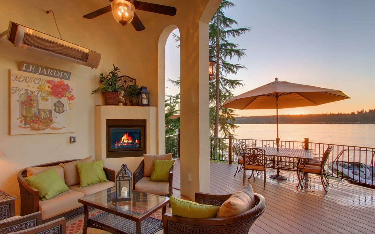 An open living room with a fireplace and a table overlooking a lake