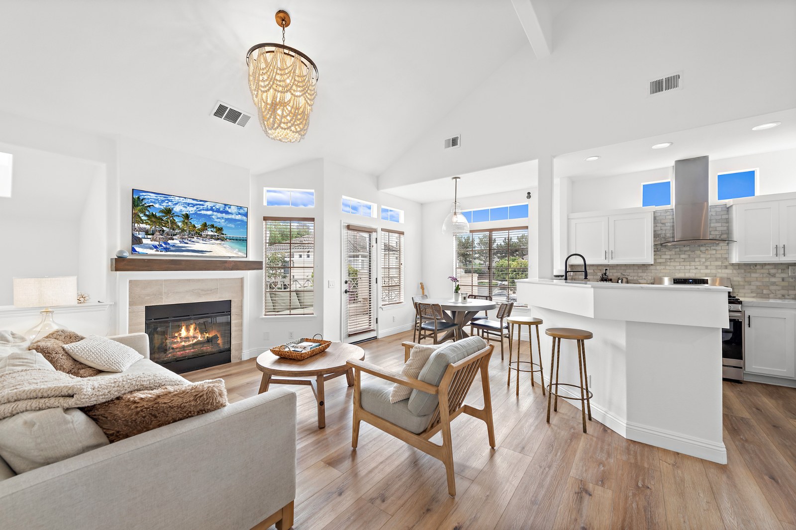 Great room with a lit fireplace, vaulted ceiling and open kitchen in a Breakers home on Shorebreaker Drive, Laguna Niguel, listed by Adam Nelson
