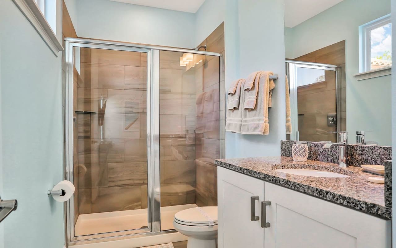 A bathroom interior with a toilet, shower, and sink.