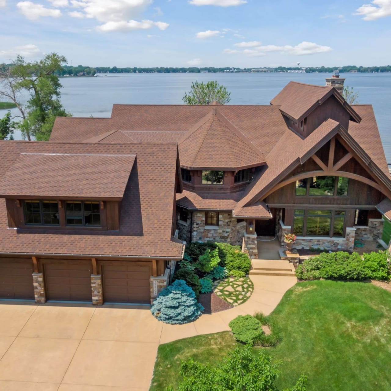 A large house with a brown roof overlooking a lake.