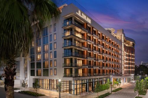 Hotel exterior featuring balconies, palm trees with sun setting