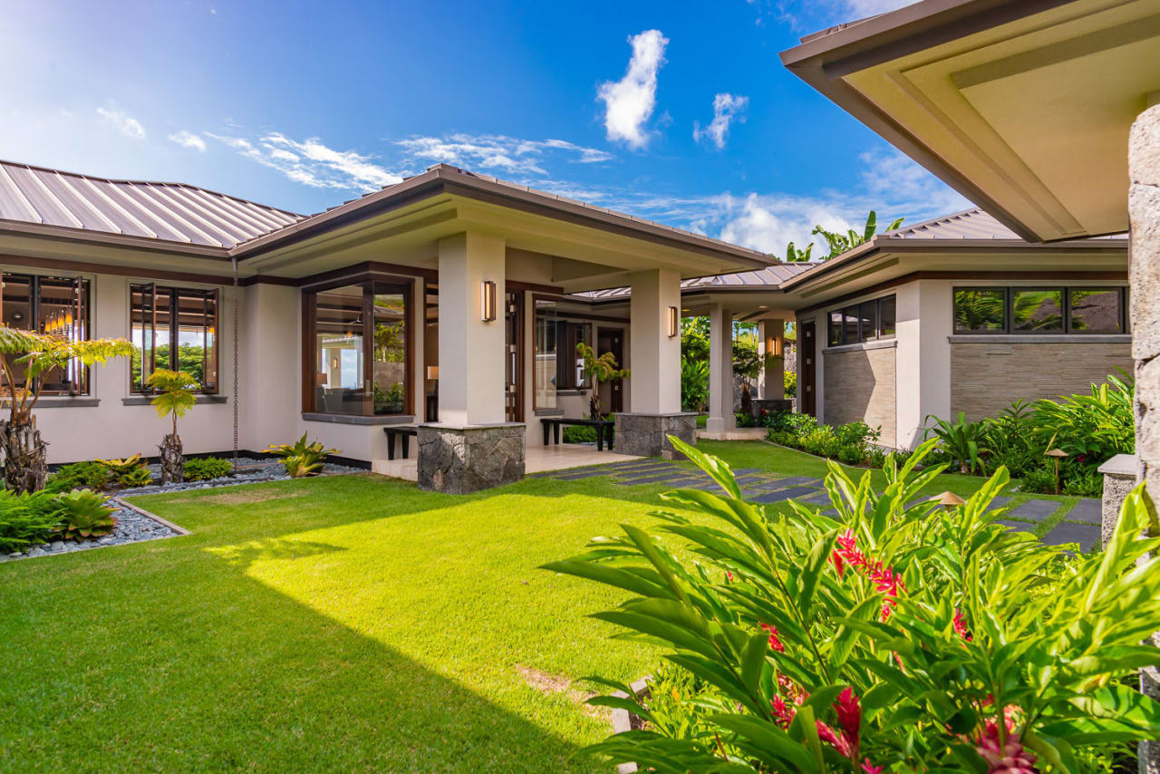 A beautiful tropical house with a lush green lawn in front of it