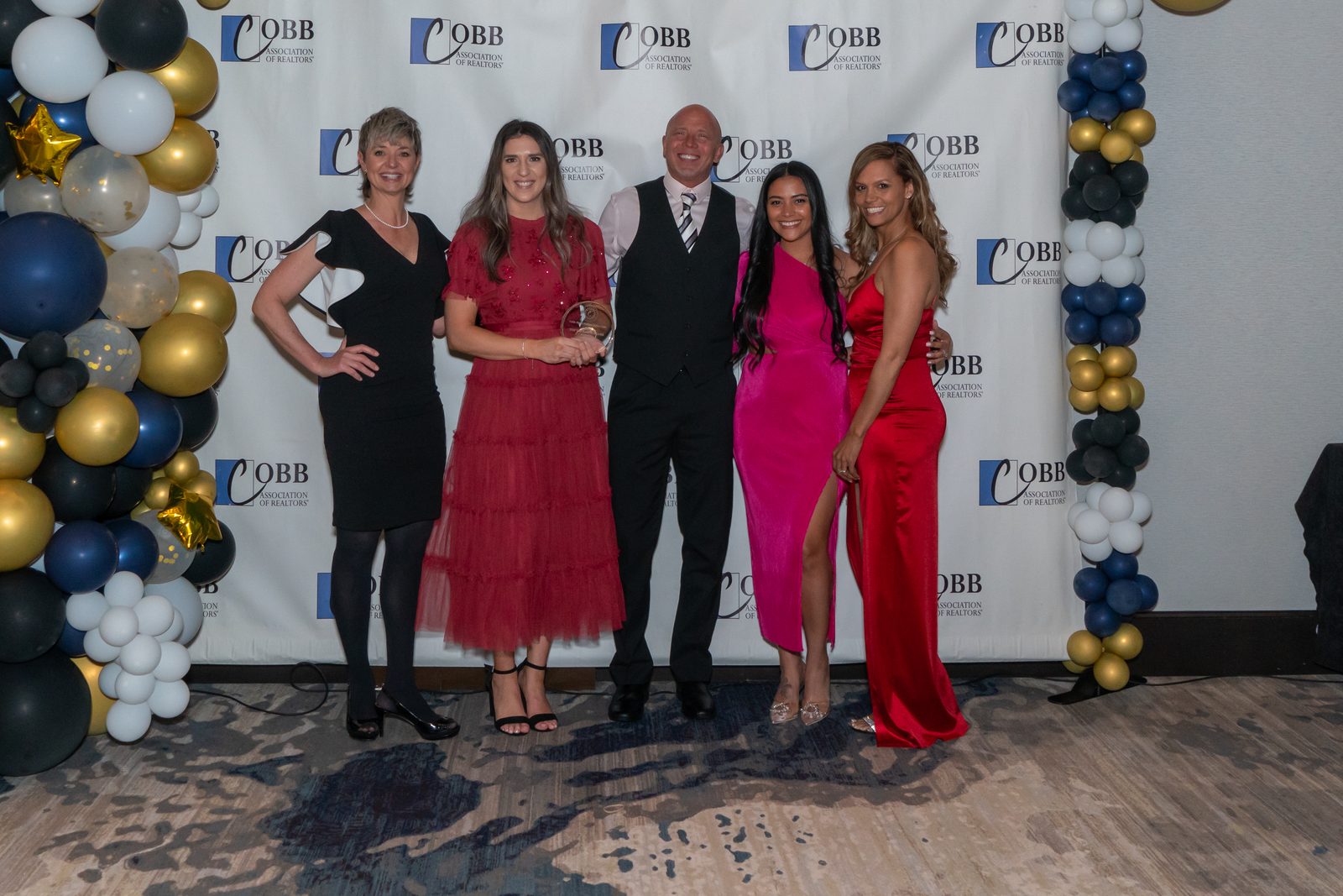 Clareo Group agents posing with an award in front of the Cobb Association of Realtors step-and-repeat at the April 2024 awards gala