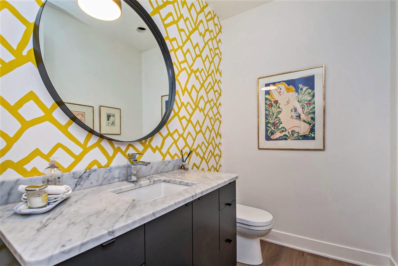 yellow patterned wall in a bathroom sink with mirror and toilet