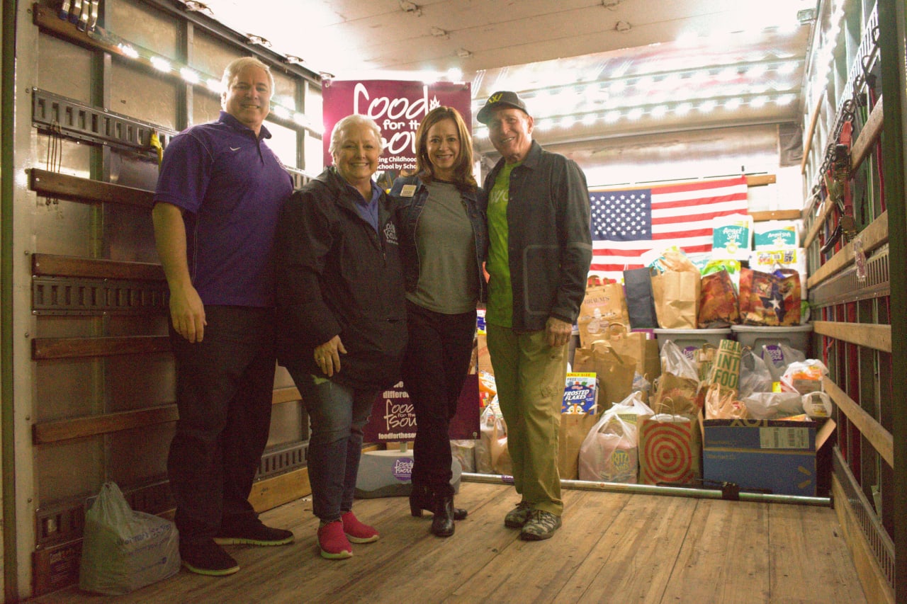 Four people in a truck filled with boxes and bags of food