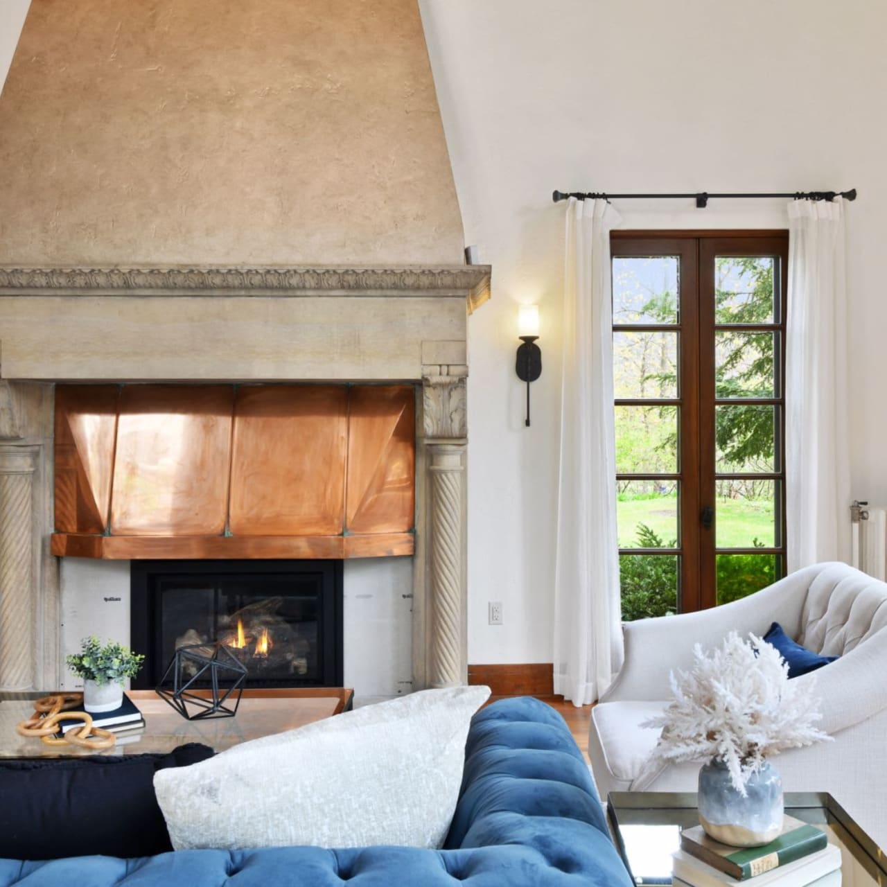 A living room with a blue couch, a white armchair, and a fireplace.