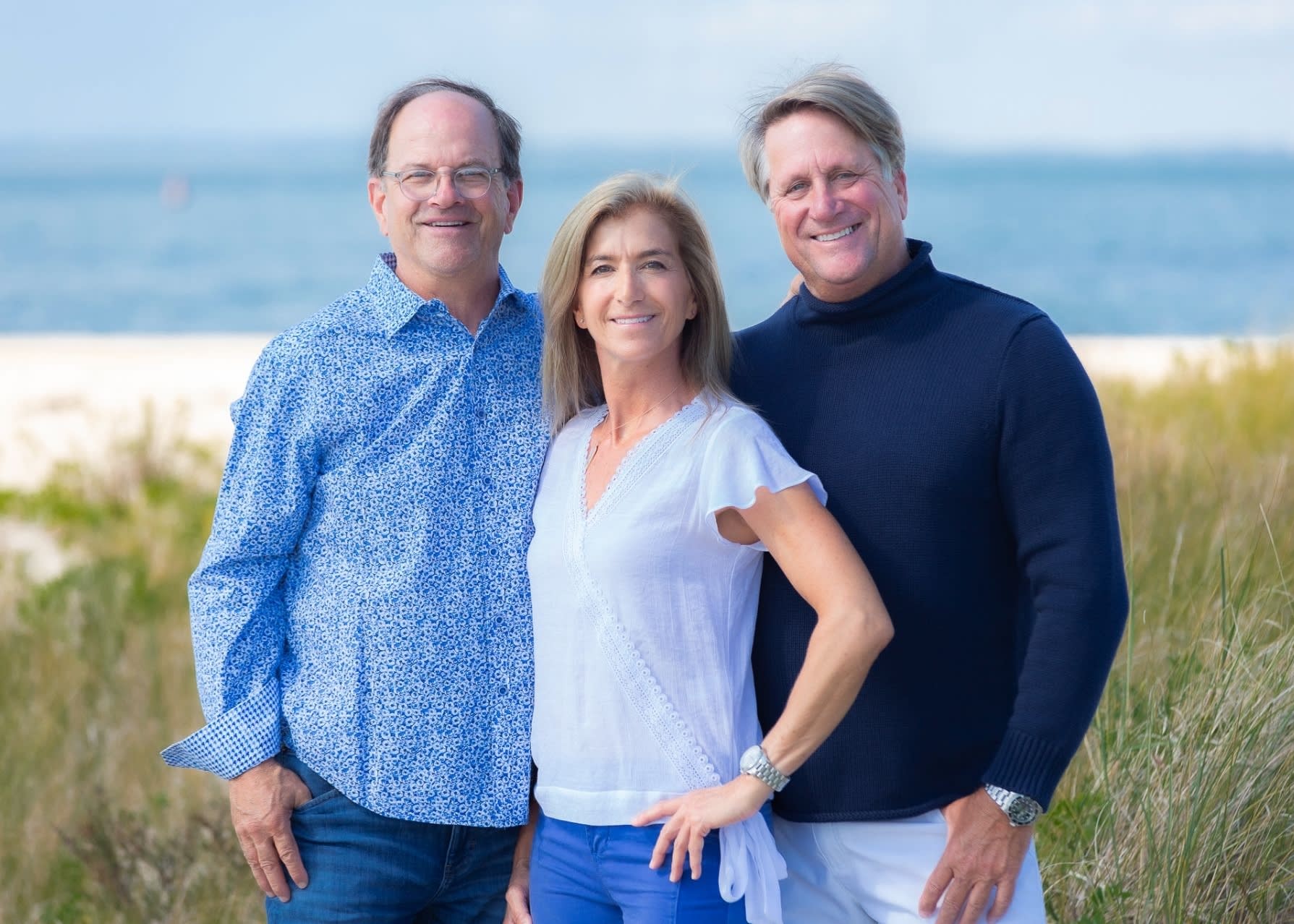 Three real estate professionals from The Bradley Team stand by the ocean, looking at the horizon.