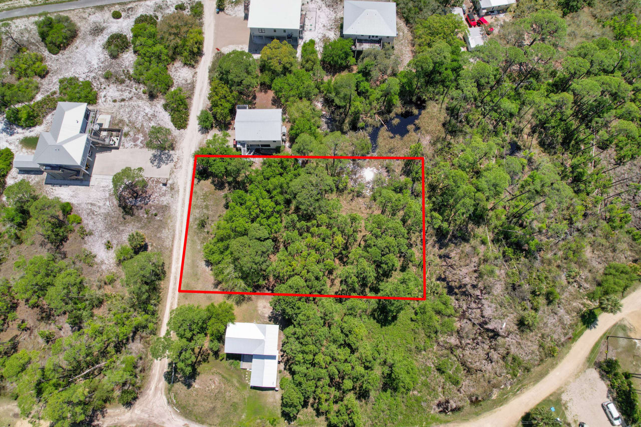 An aerial view of a plot of land within a residential area, marked by a red border, indicating the property boundaries.