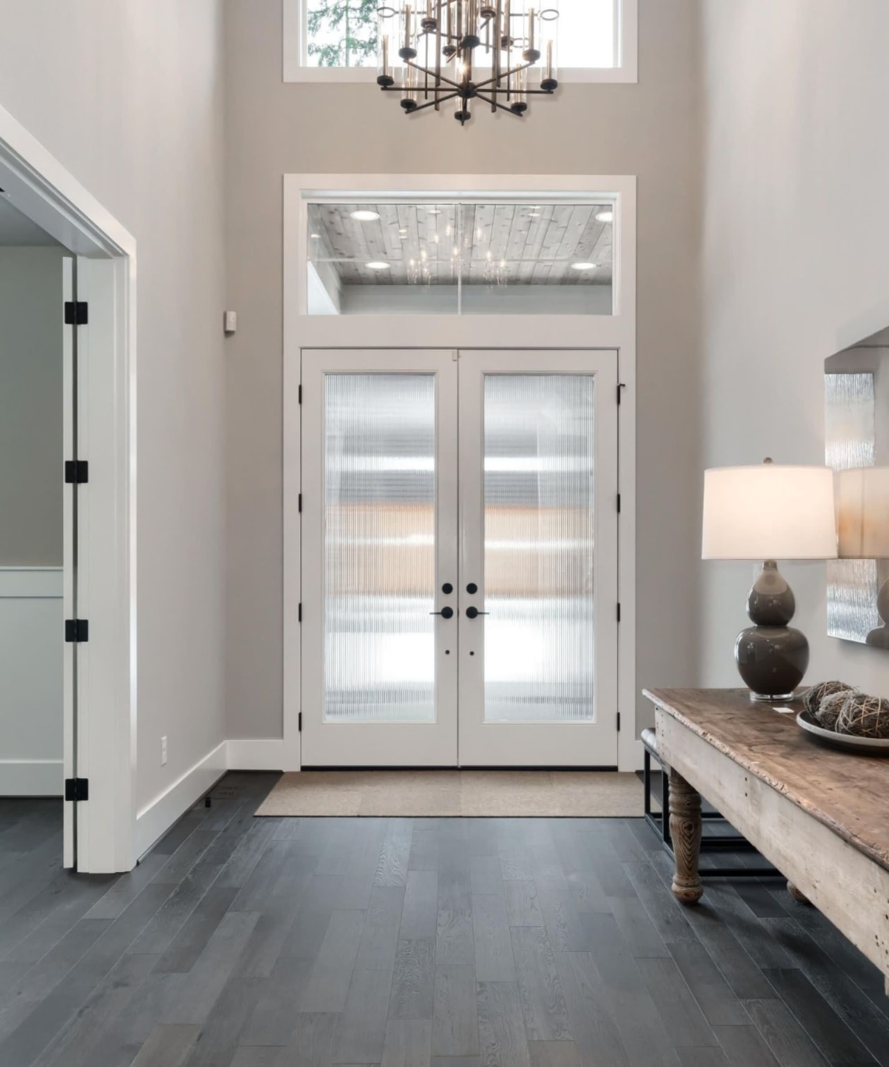 A hallway with a table and a chandelier