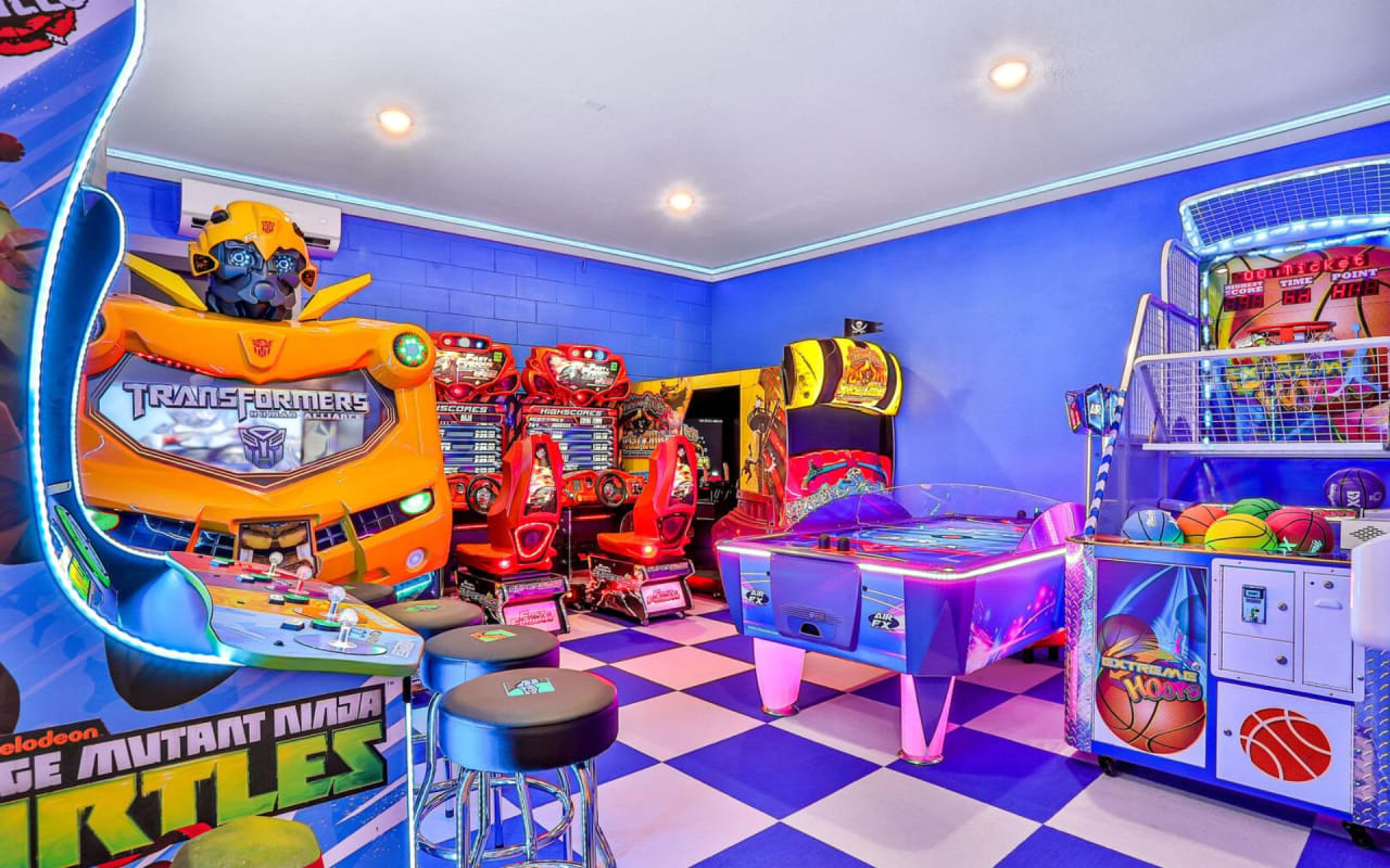A brightly lit game room filled with arcade games, air hockey tables, and basketball hoops.