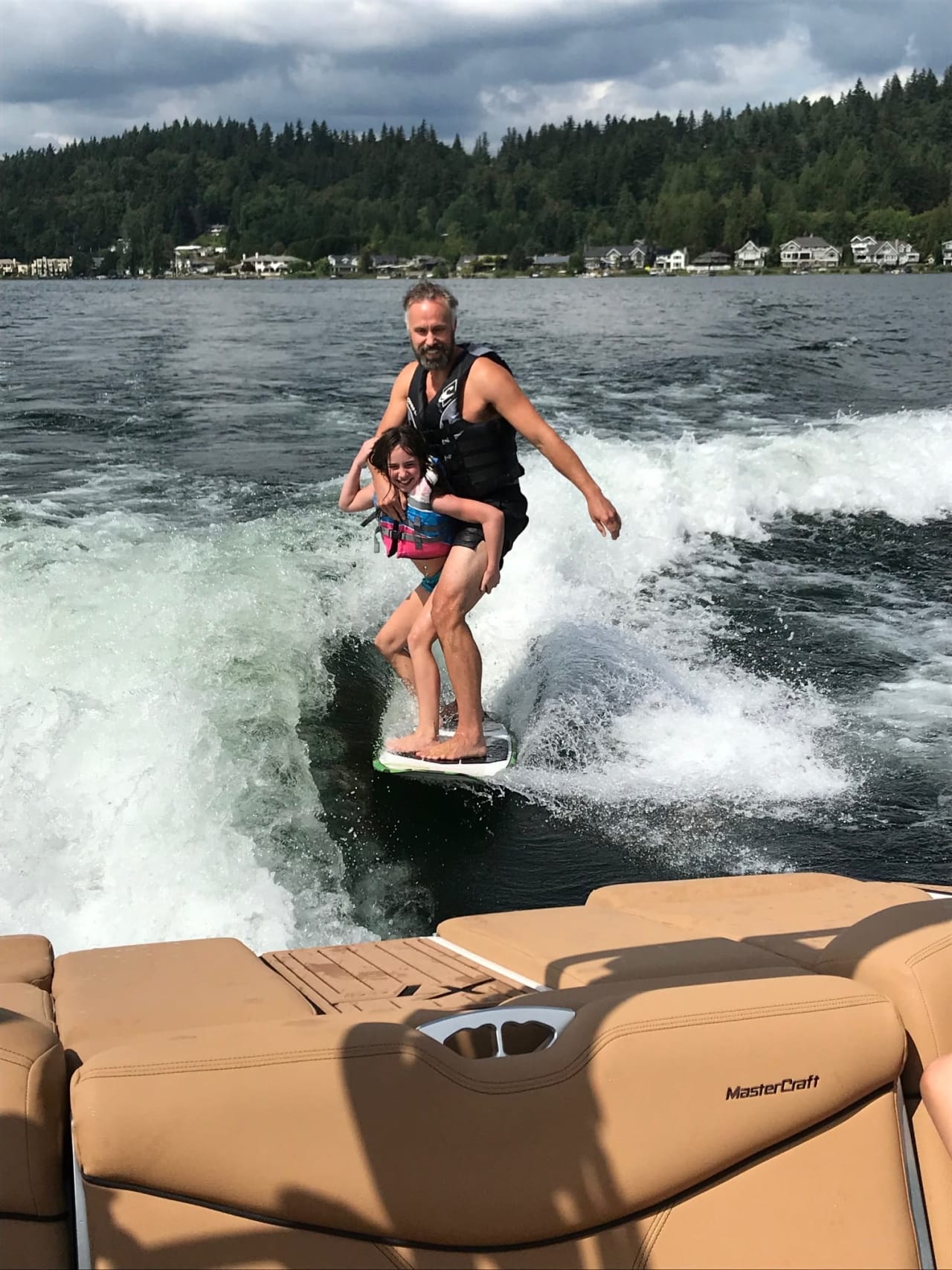 father and daughter wakeboarding behind a boat on a lake