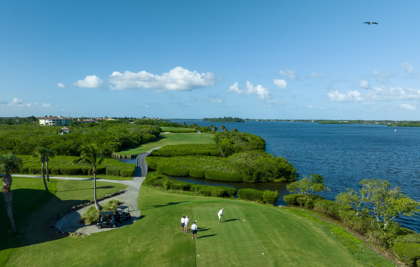 Golfers on a riverfront tee box along the Indian River Lagoon at a Vero Beach country club