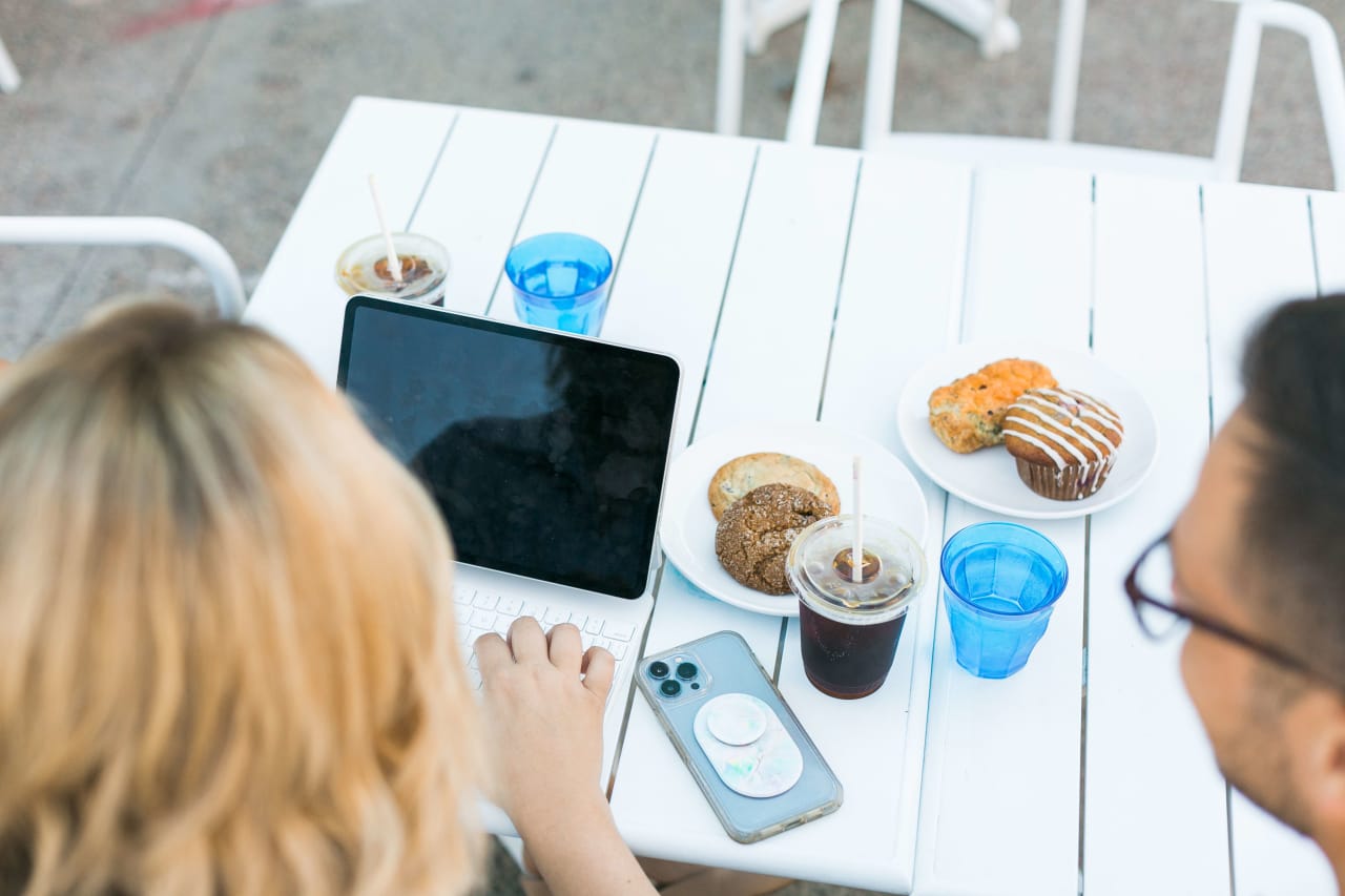 Real estate professionals from the Insiders Realty, sitting at a table with a tablet and cupcakes, engaged in a conversation.