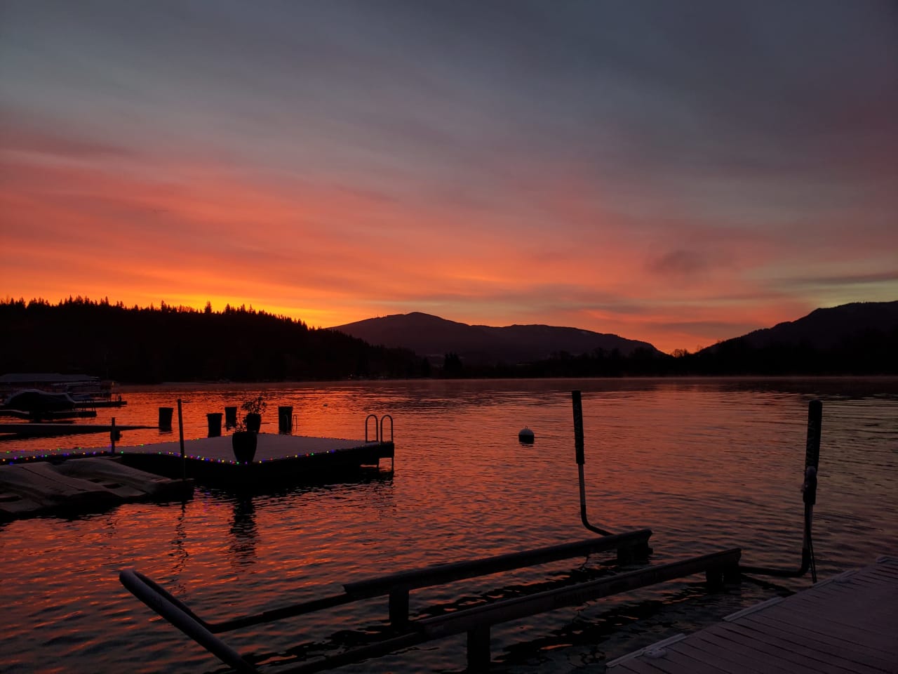 A sunset over a lake with a dock in the foreground