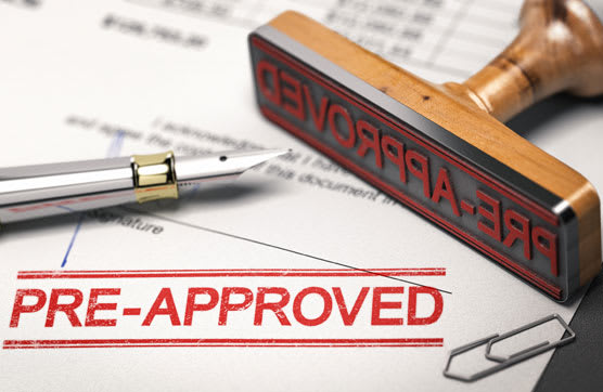 A rectangular stamp with the words "pre-approved" in red ink on a document.