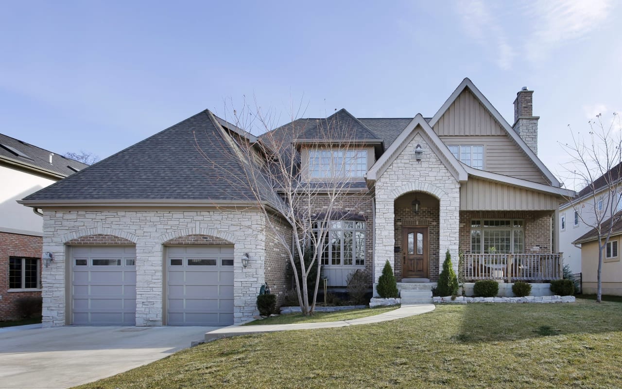 A large brick house with a gray roof and a two-car garage.