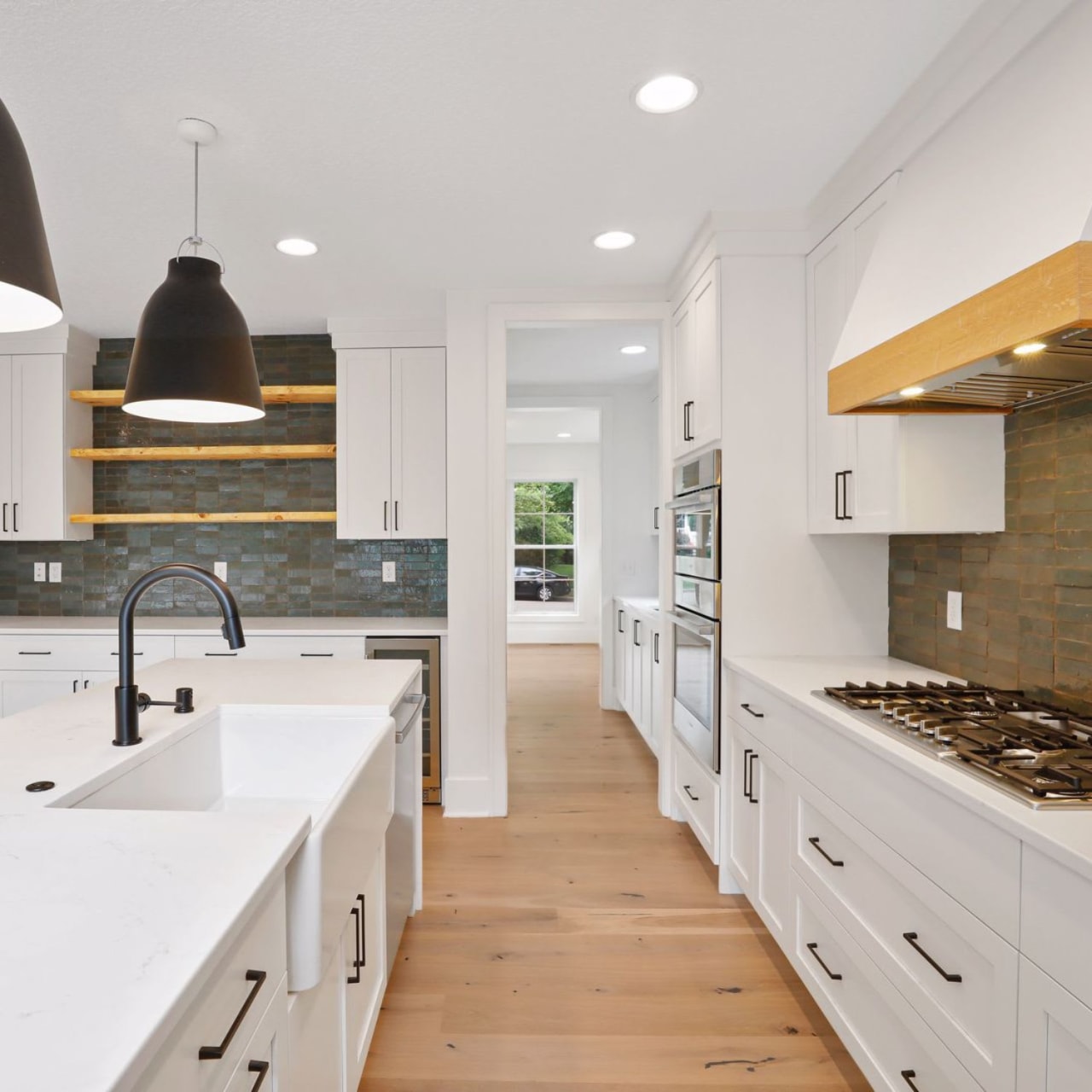 A kitchen with a sink and faucet on the left side and a stove with a vent hood on the right side.