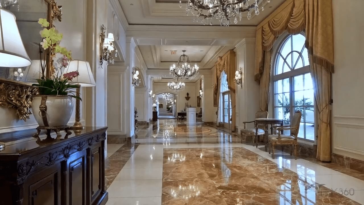 A luxurious hallway in The Beach Residences with marble floors, chandeliers, and intricate architecture