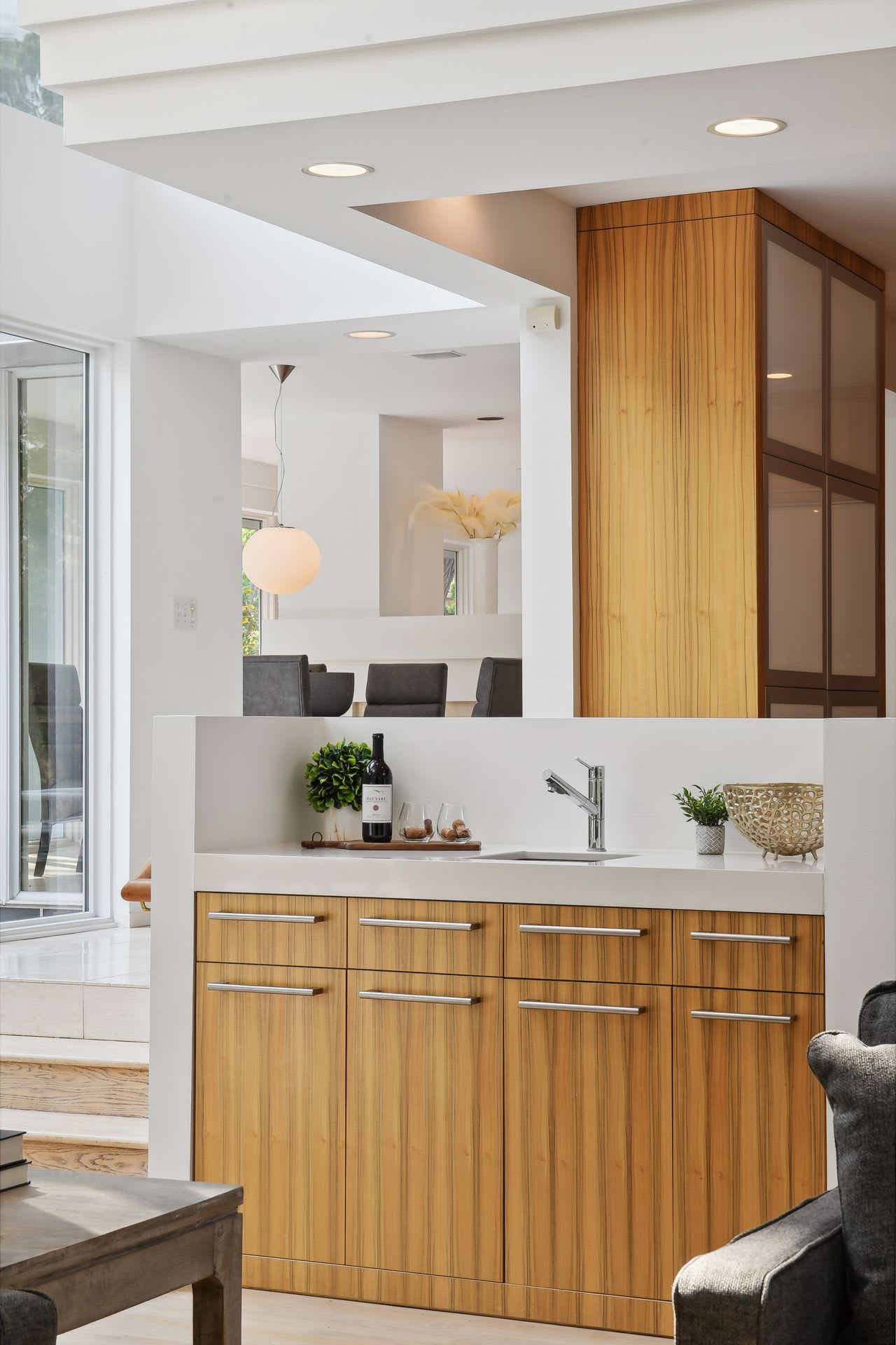 A counter with wooden cabinets, a sink, and a bottle of wine on the countertop.