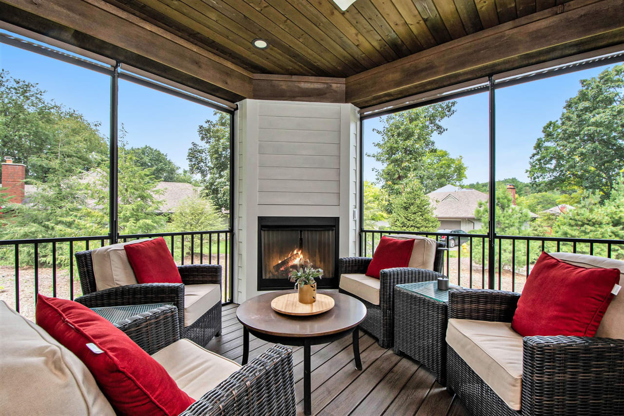 A screened-in porch with wicker furniture and a fireplace