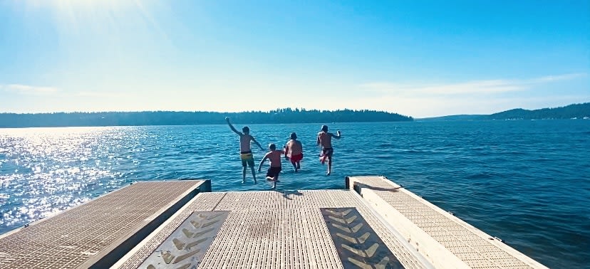 four people jumping on a boat dock on a sunny day