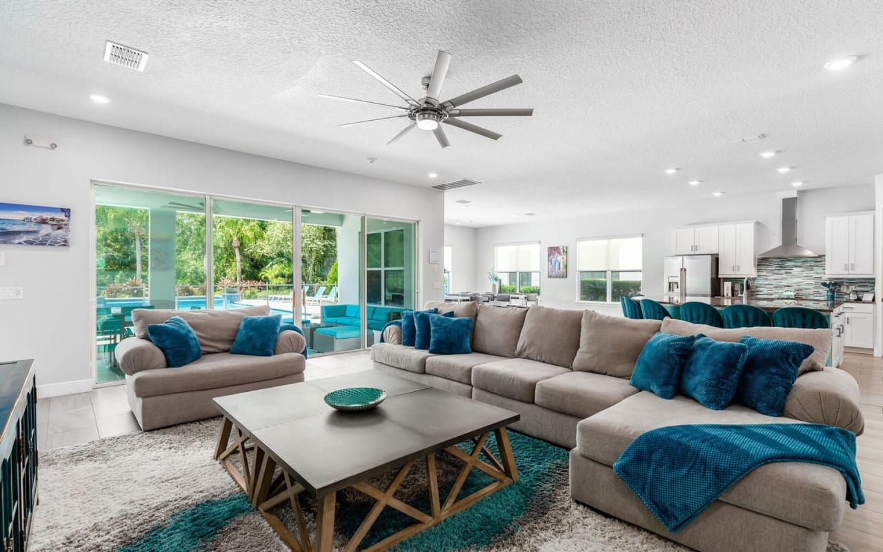 A modern living room with a brown leather couch, two brown accent chairs, and a round wooden coffee table.