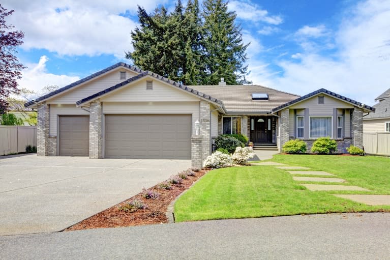 A large house with a gray garage door and a long driveway.