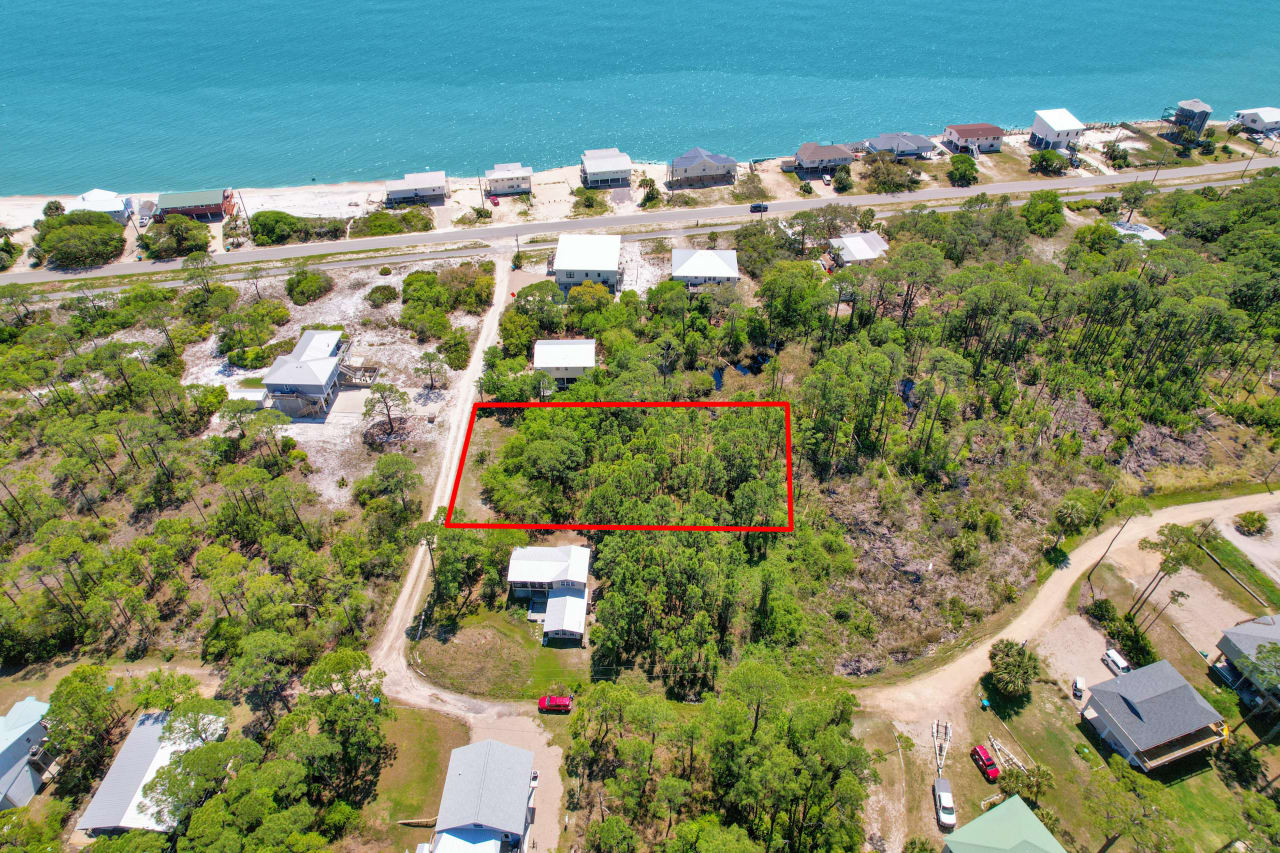 An aerial view of a residential area with a marked plot of land, showing the layout of houses and proximity to the water.