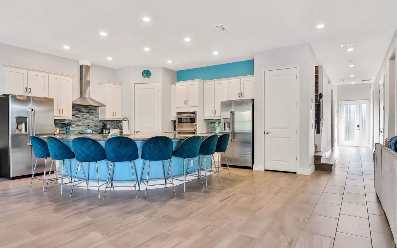 A large kitchen with a spacious center island with cushioned bar stools.