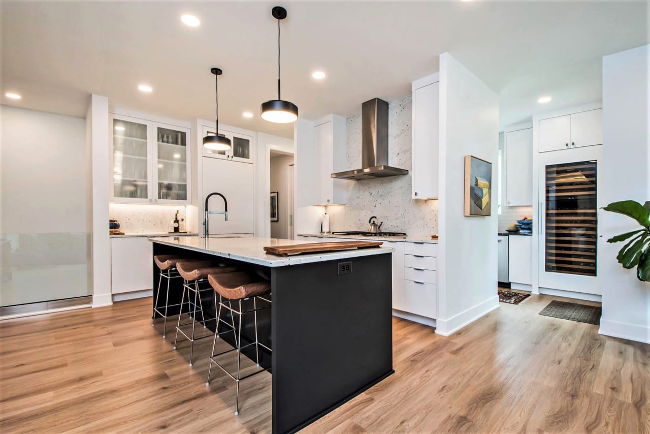 A kitchen with a large island and stools and granite counter top