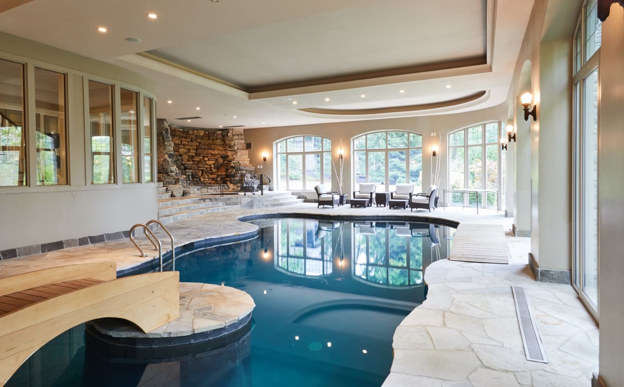 Large indoor pool with windows, wooden bridge in the center.