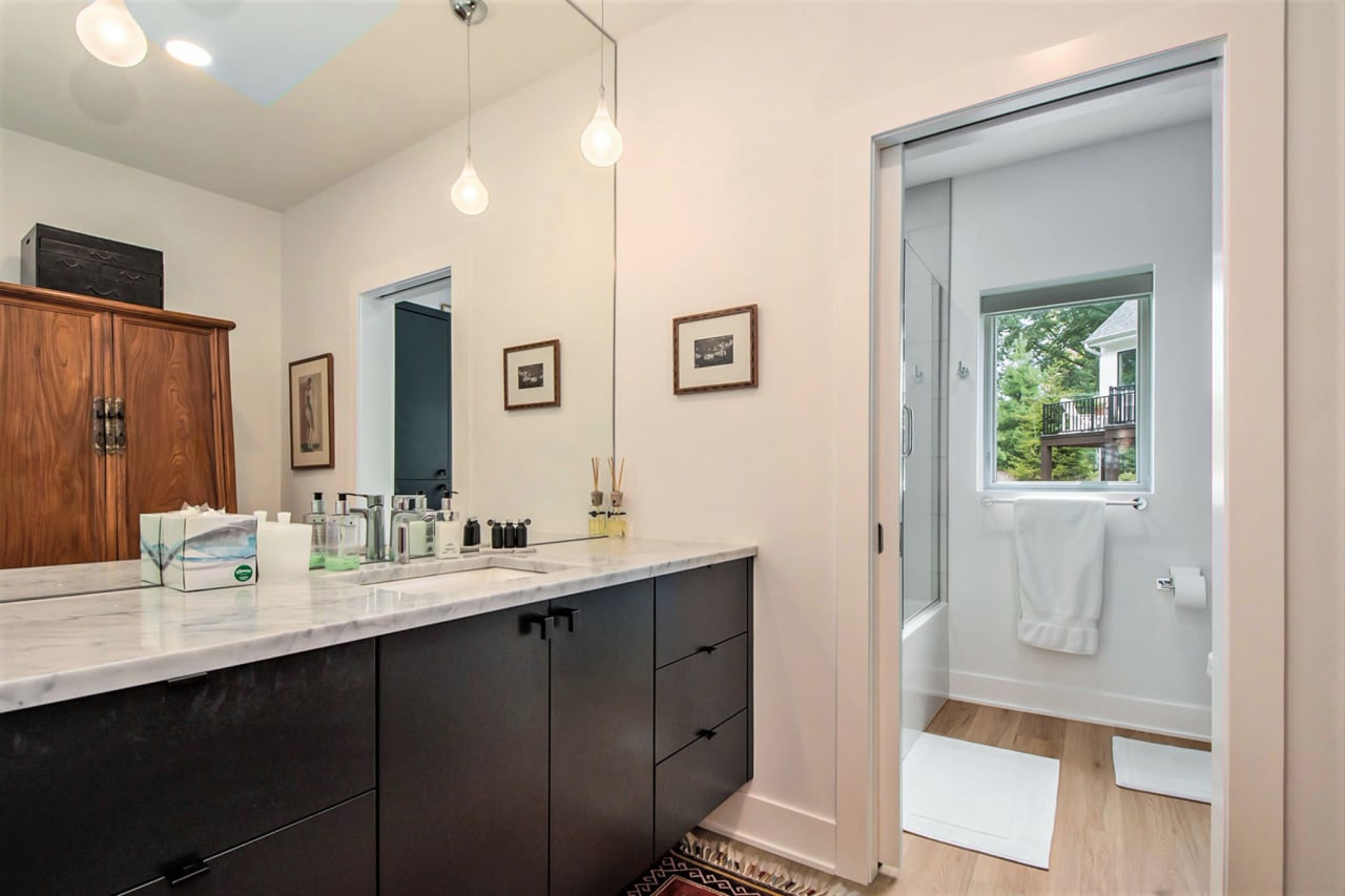 A bathroom with a vanity, mirror, and door going to the toilet and shower