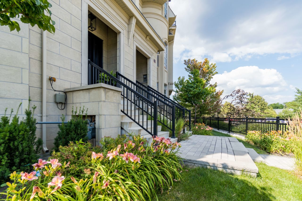 The front of a house with a black metal fence and a flower bed.