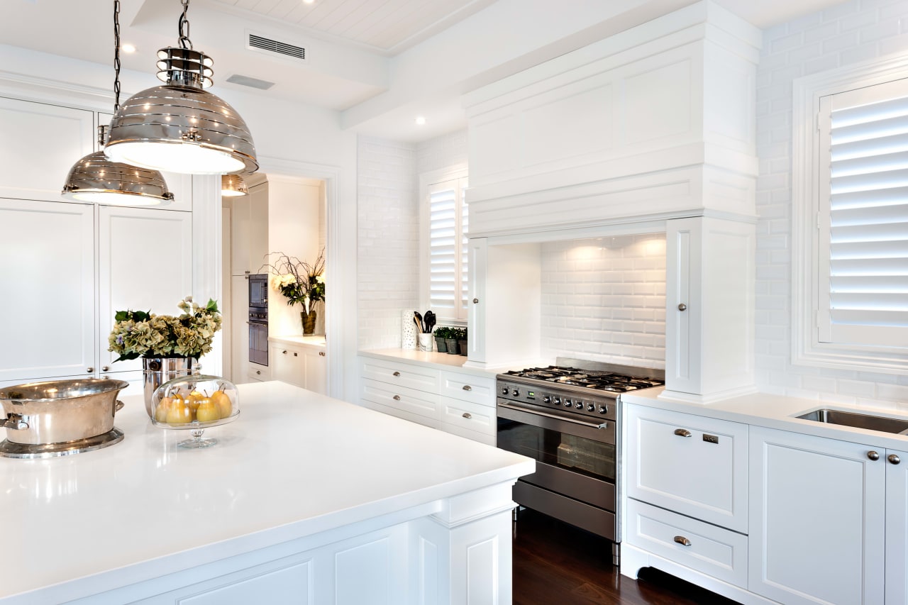 Clean white kitchen with black stove and stainless steel sink.