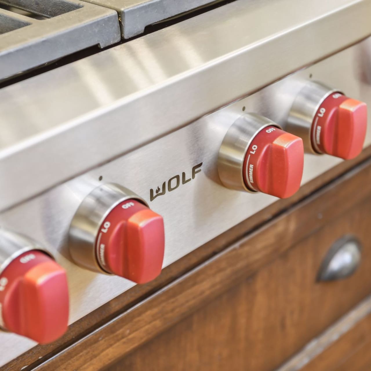 A stainless steel stovetop oven with four burners and red knobs.