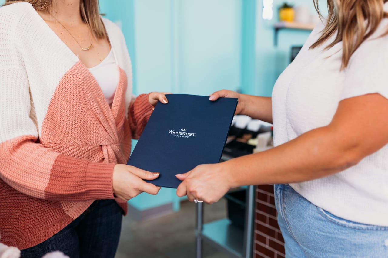 Samara and other real estate agent look over Windermere Real Estate documents.