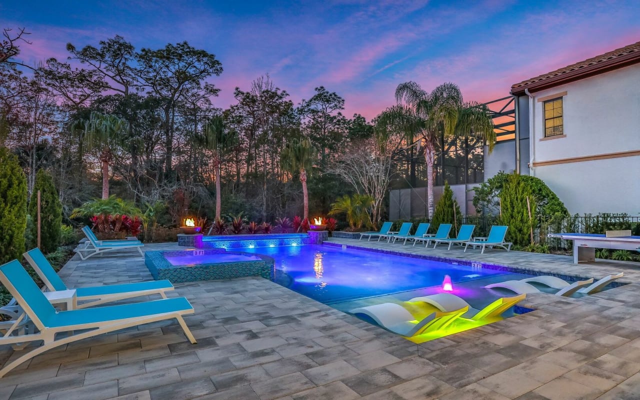 A large, inviting swimming pool with a blue liner in a twilight outdoor space.