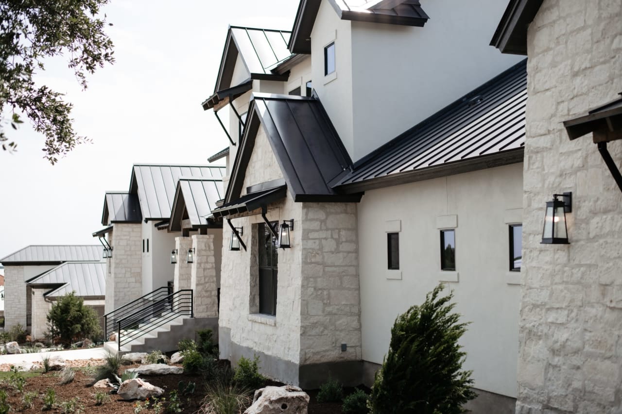 A white house with a black metal roof. 