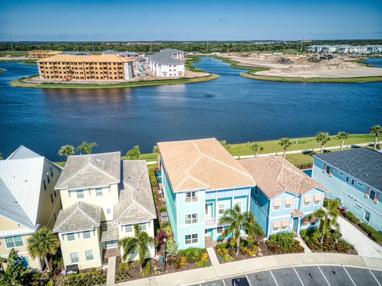 A row of colorful houses in a variety of styles line a lake.