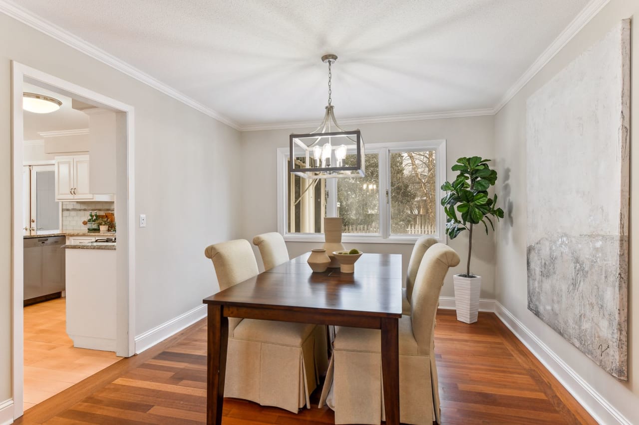 A staged dining room with a wooden table, chairs, and a chandelier.